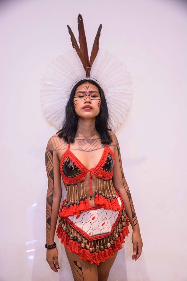 Modelo indígena com traje nas cores laranjas e branco