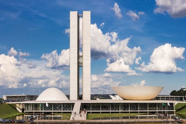 Congresso Nacional, sede do Parlamento Brasileiro em Brasília (DF), vista frontal.  Ao fundo o céu é azul com algumas nuvens - Metropolis