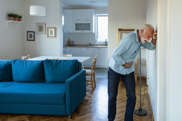 Man leaning against wall and bending over as if in pain.  He has white hair - Metropolis