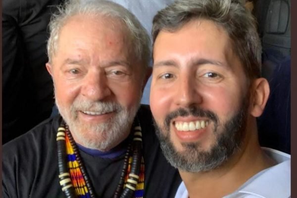Lula tira selfie com o pré-candidato e deputado distrital Leandro Grasss, no acampamento indígena Terra Livre. Ambos sorriem - Metrópoles