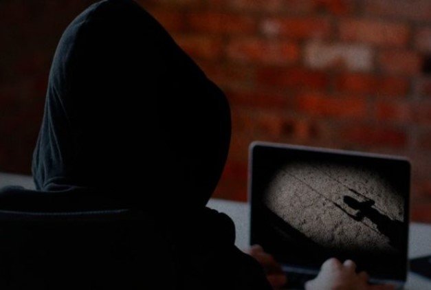 A man in a dark hood stares at a computer screen - Metropolis