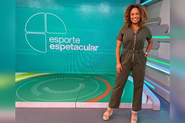 Karine Alves, jornalista global.  Ela tem cabelos cacheados e usa roupa verde - Metrópoles