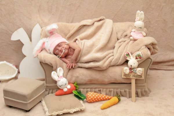 bebê dorme em sofázinho com manta e placa de "feliz páscoa"