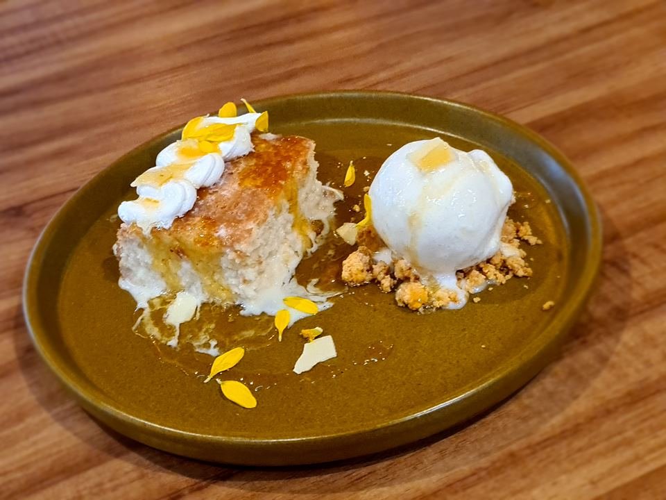Sobremesa Três Leches, composta por bolo de laranja embebido em três tipos de leite, servido com sorvete de gengibre e calda morna de laranja, prato do restaurante Kinjo - Metrópoles