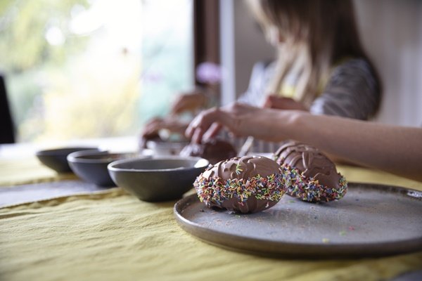 duas mulheres decoram ovos de chocolate artesanais