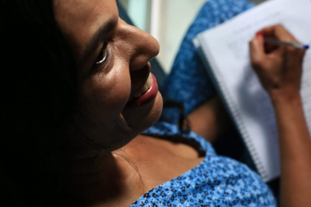 Mulher sorri enquanto escreve em caderno-Metrópoles