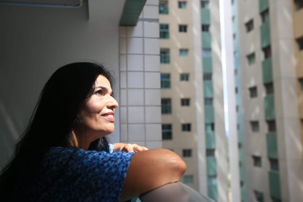 A mulher observa o céu enquanto está encostada em batente da janela-Metrópoles