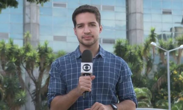 Gabriel Luiz, repórter da TV Globo, segurando microfone