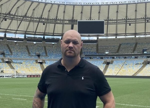 homem de camisa preta em pé no gramado do maracanã