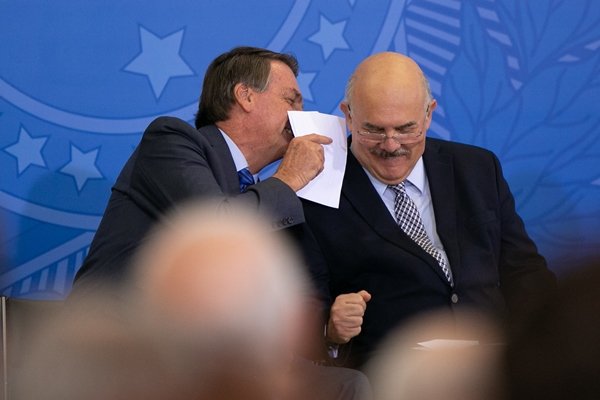 Foto colorida do presidente Jair Bolsonaro ao lado do ministro Milton Ribeiro em cerimônia no Palácio do Planalto