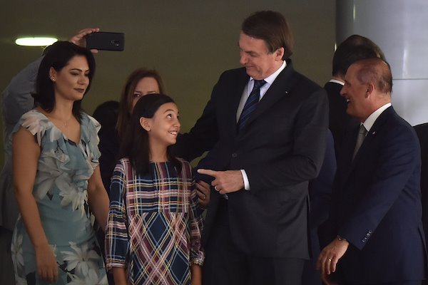 Foto colorida do presidente Bolsonaro ao lado de sua filha, Laura Bolsonaro, e mulher, Michelle Bolsonaro em apresentação da Cantata de Natal no Palácio do Planalto