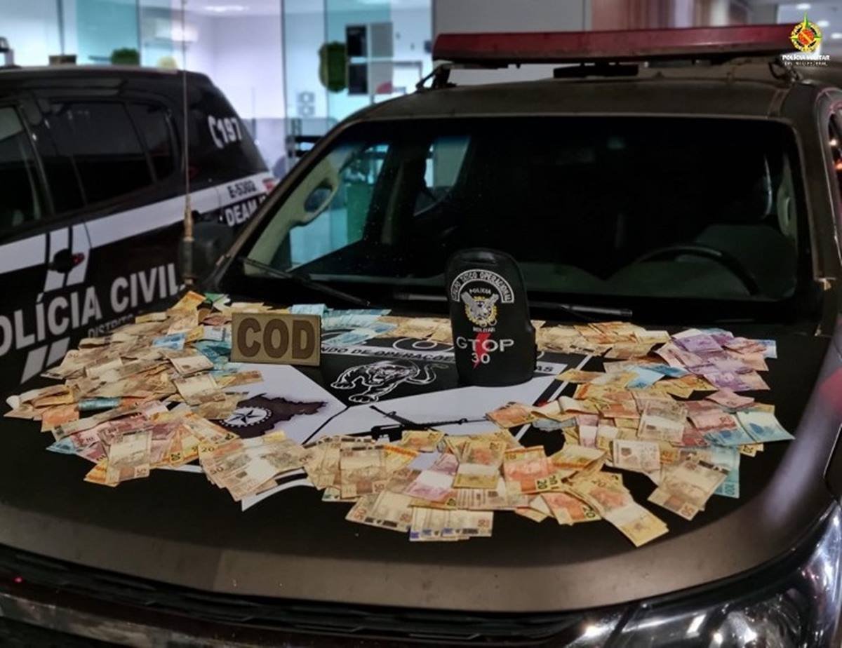 fotografia colorida de dinheiro em espécie apreendida em cima de carro da polícia civil