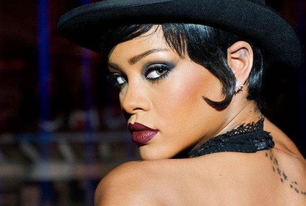 Rihanna, cantora e atriz internacional.  Ela tem pele negra, cabelos longos, escuros e tem olhos claros- Metrópoles