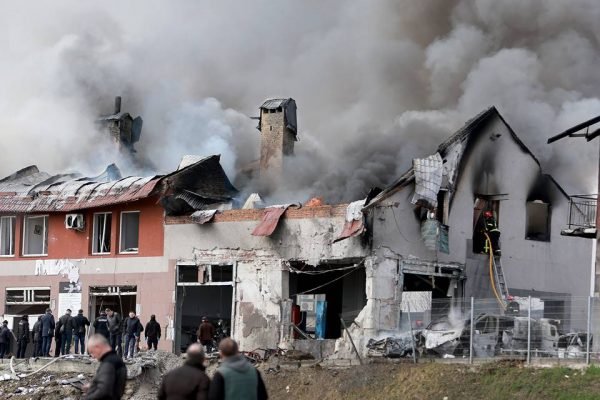 Cidade de Lviv, na Ucrânia, é bombardeada por misseis russos. Na foto, várias casas aparecem destruídas e muita fumaça sai delas, enquanto pessoas se aglomeram na frente - Metrópoles