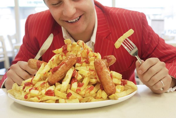 Pessoa com garfo e faca nas mãos olhando para um prato com batata frita - Metrópoles