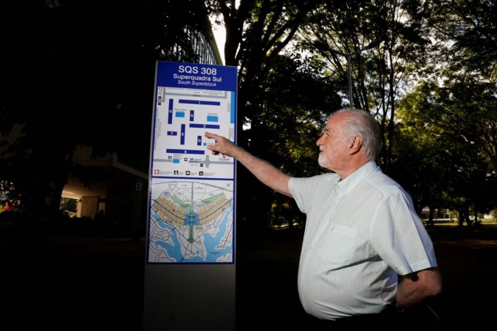 Homem de camisa social aponta para placa