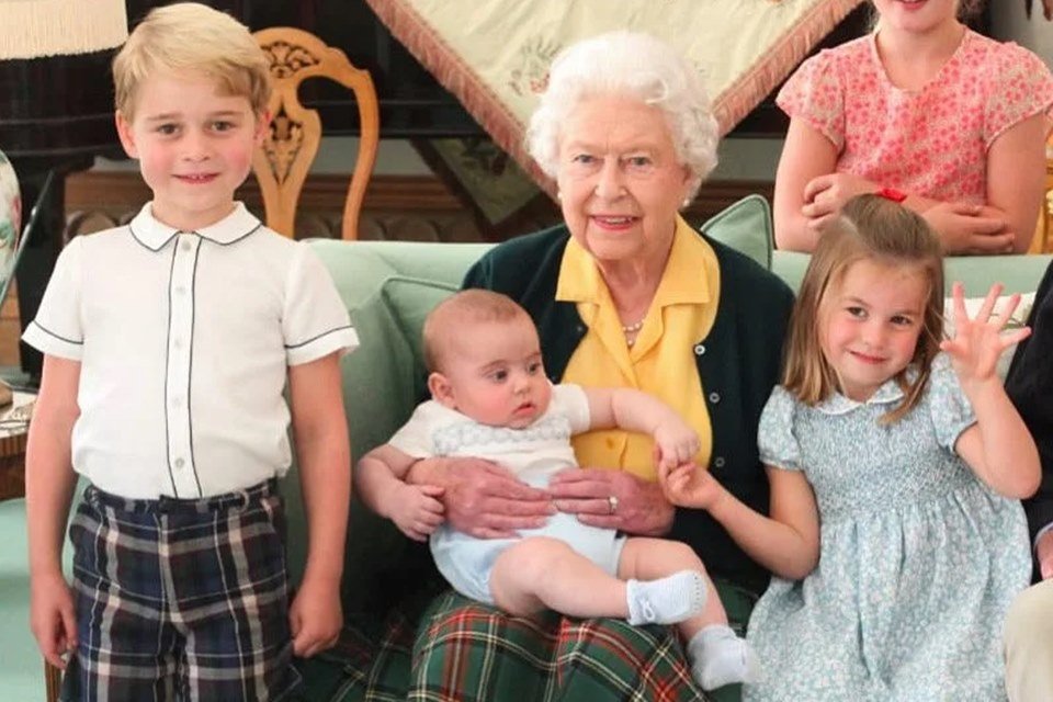 Foto colorida.  Rainha Elizabeth, princesa Charlotte, príncipe George e príncipe Louis