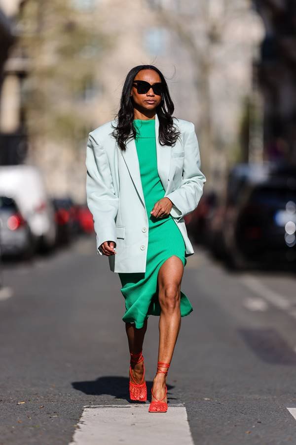 Look de street style com vestido verde, blazer oversized cinza claro e sandália de salto vermelha