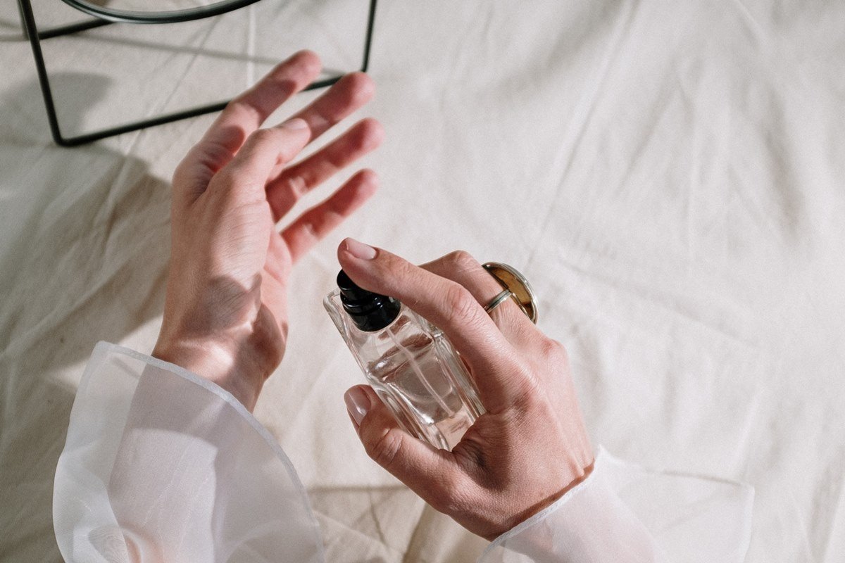 Mãos aplicando perfume