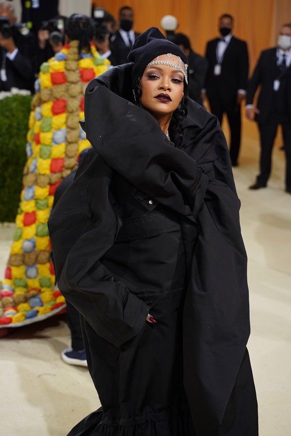 Cantora Rihanna no baile do Met Gala em 2021. Ela usa um vestido que mais parece uma capa preta com joias prateadas e com diamantes.