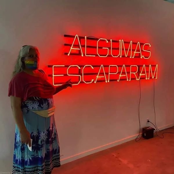 mulher mostra letreiro vermelho pregado na parede branca