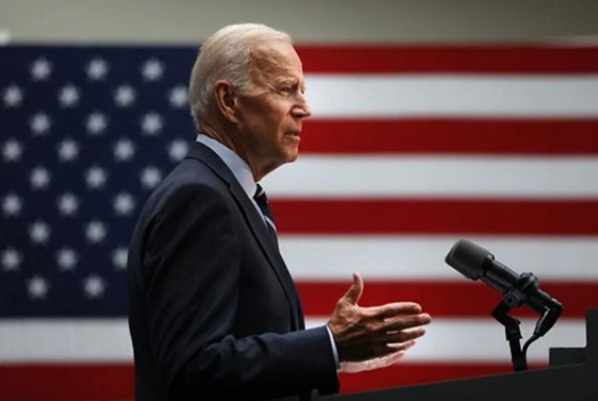 presidente dos EUA Joe Biden discursa em um palanque. é possível ver, em destaque, a bandeira do país ao fundo