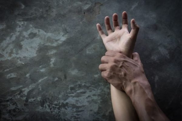 Imagem colorida de mão de homem segurando pulso de mulher em um ato de crime de estupro - Metrópoles