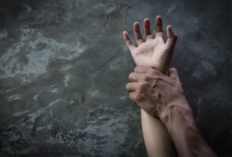 Imagem colorida de mão de homem segurando pulso de mulher - Metrópoles