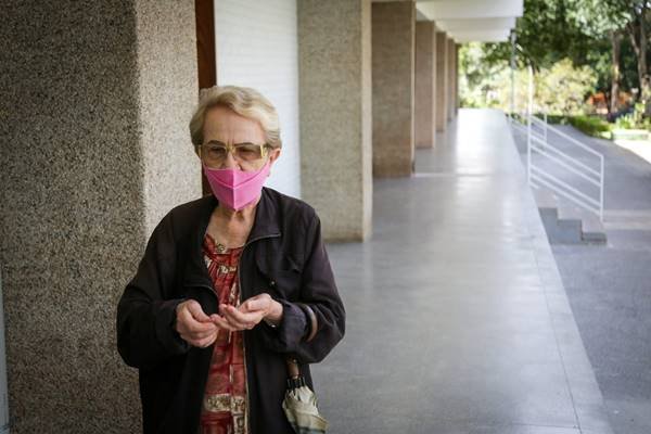 Fotografia colorida mostra idosa com máscara rosa