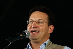O pré-candidato ao governo da Bahia e ex-ministro de Bolsonaro, João Roma fala ao microfone em evento. Ele usa colete bege e camisa social azul - Metrópoles