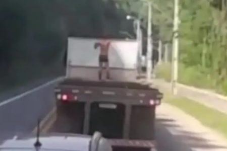 Homem em cima da carroceria de caminhão em BR