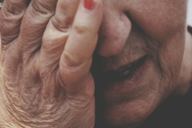 Mulher idosa com uma das mãos no rosto - Metrópoles