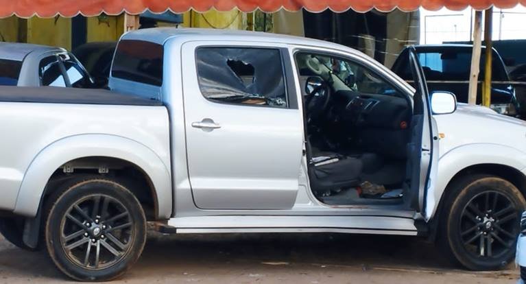 Caminhonete prata com marca de tiro em janela e porta aberta