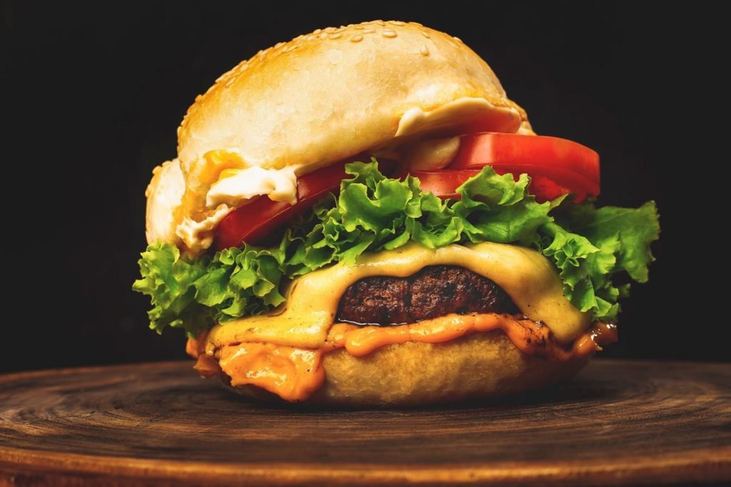 Imagem de um hamburguer com salada em fundo preto - Metrópoles