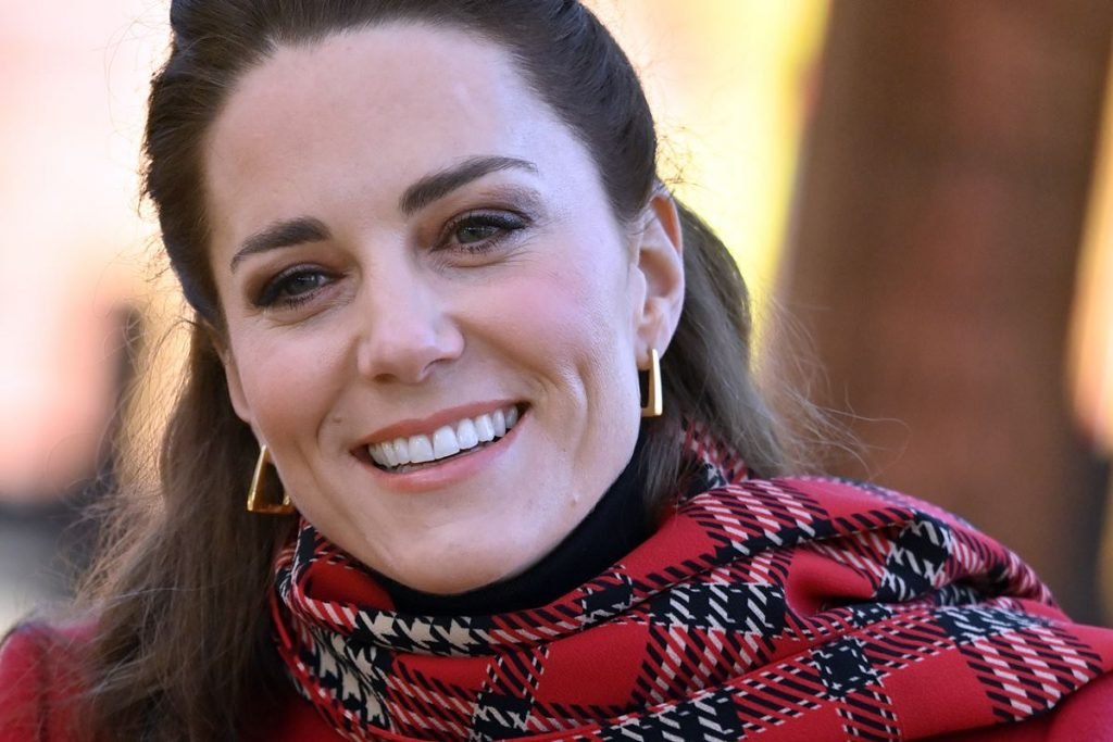 Na foto, mulher branca com cabelo castanho usa roupa em tom vermelho - Metrópoles