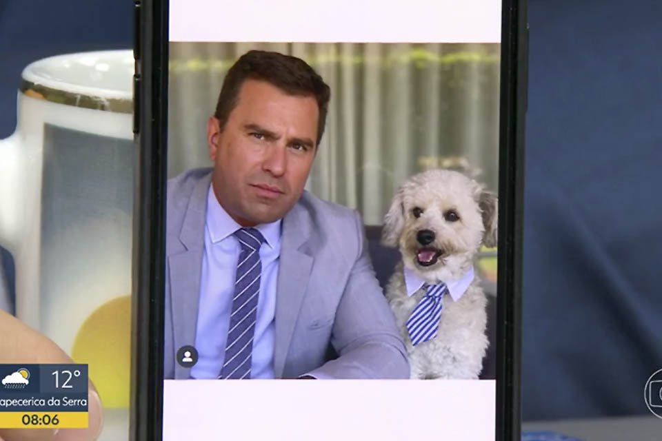 O apresentador Rodrigo Bocardi mostra no Bom Dia SP seu cãozinho, Gaspar, usando gravatinha em tela de celular - Metrópoles