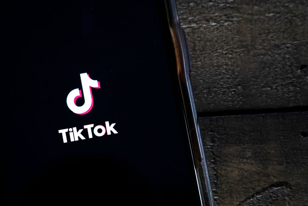 Celular sob mesa mostra aplicativo e logo do TikTok - Metrópoles