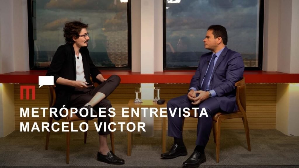 Thumbnail da entrevista com o deputado Marcelo Victor, presidente do poder legislativo de Alagoas. Ele é entrevistado pelo jornalista do Metrópoles, Tácio Lorran, ambos frente a frente num estúdio, sentados - Metrópoles