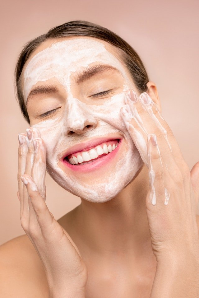Mulher com mãos no rosto aplicando produto na pele