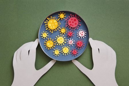 Ilustração colorida de uma pessoa mexendo numa placa de petri com representações do coronavírus - Metrópoles