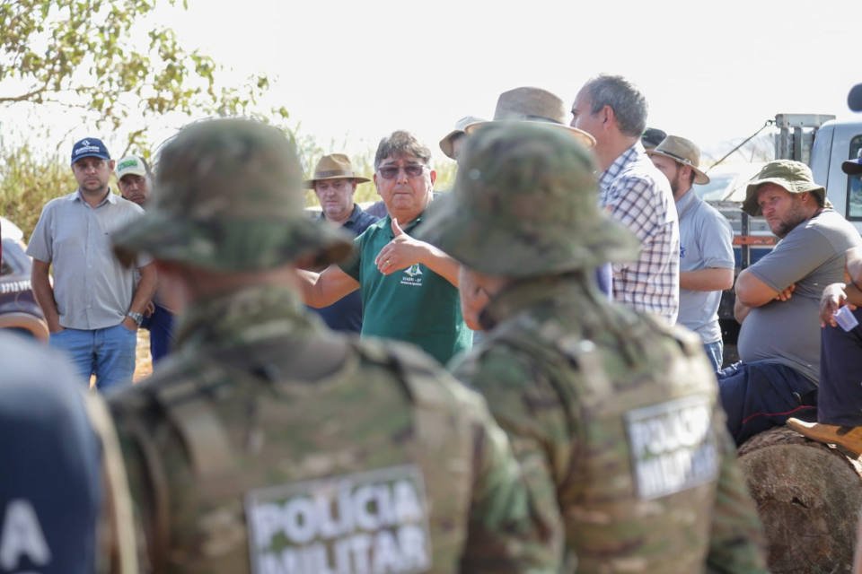homem de camiseta verde com policiais na frente