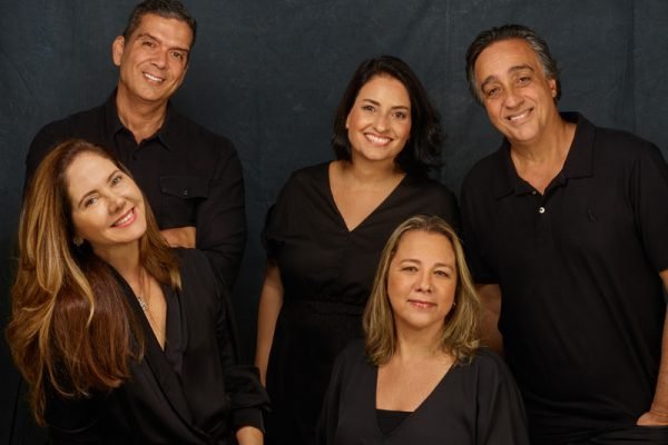 Equipe da empresa Approach Comunicação, todos usando preto sob fundo da mesma cor - Metrópoles