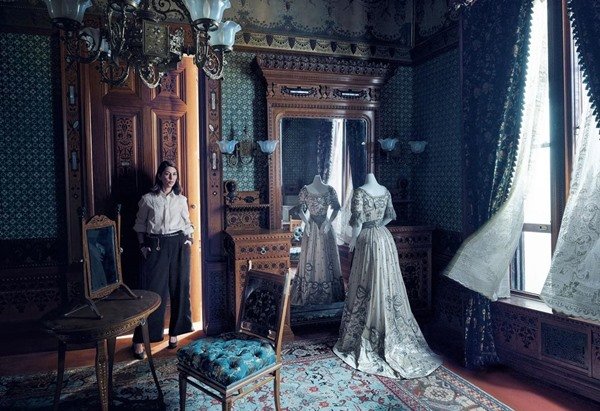 Film director Sofia Coppola, a white woman with short, wavy hair, posing for a photo in one of the rooms at the new Costume Institute exhibition at the Metropolitan Museum of Art in New York.  In the background you can see mannequins wearing 18th century clothes.