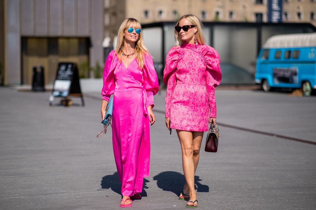 Duas mulheres loiras caminhando na rua. Ambas estão com roupas rosas e chinelo nos pés