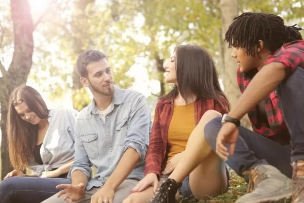 quatro jovens conversando sentados em um banco em um parque