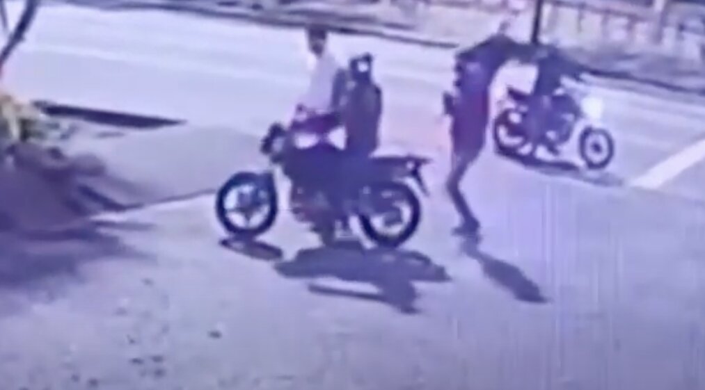 Um dos criminosos puxa o paletó, e em seguida a vítima retira a peça de roupa