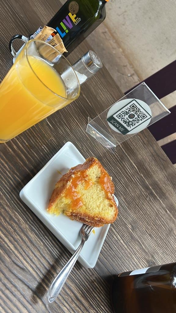 Suco amarelo em copo e prato branco com bolo em mesa de madeira