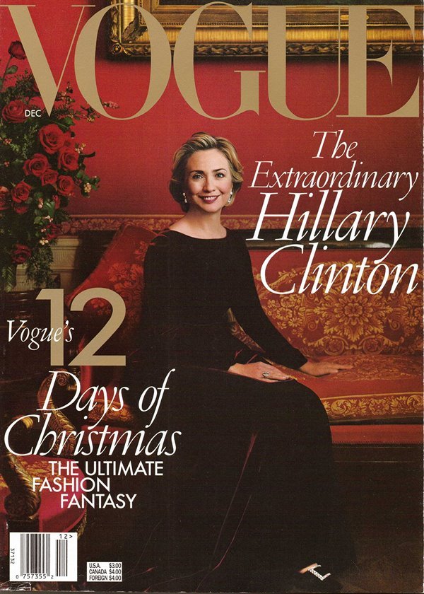 A ex-primeira dama e ex-candidata à presidência da república dos Estados Unidos, Hillary Clinton, em capa da revista Vogue de 1998. Ela é uma mulher idosa de pele clara e cabelos curtos e louros. Na foto, ela está sentada em um sofá vermelho e usa um vestido longo preto.