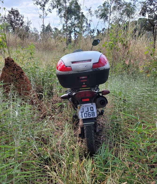 Traseira de motocicleta. Moto está em matagal