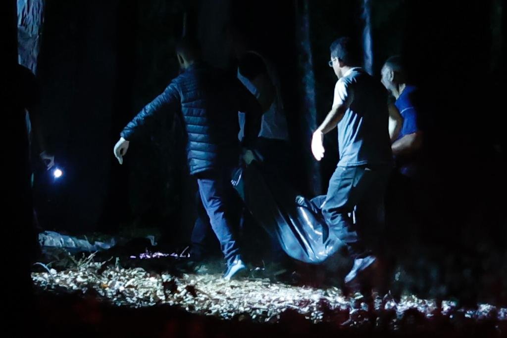 Homens carregam sacola em mata à noite